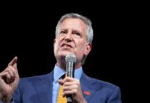 Bill de Blasio speaking into a microphone on stage