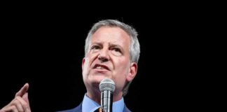 Bill de Blasio speaking into a microphone on stage