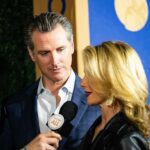man in suit listening as woman speaks into a microphone