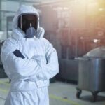 Worker in hazmat suit with respirator in industrial facility