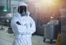 Worker in hazmat suit with respirator in industrial facility