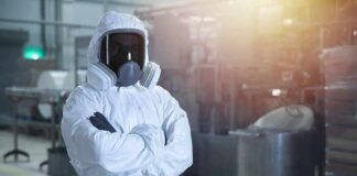 Worker in hazmat suit with respirator in industrial facility