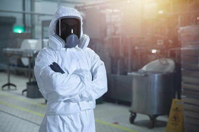 Worker in hazmat suit with respirator in industrial facility