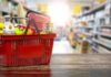 Red shopping basket filled with groceries on a store aisle