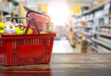 Red shopping basket filled with groceries on a store aisle