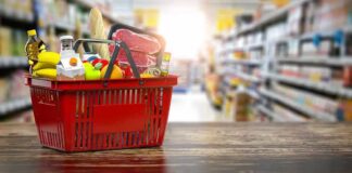 Red shopping basket filled with groceries on a store aisle