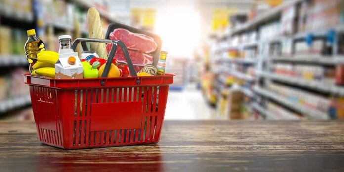 Red shopping basket filled with groceries on a store aisle