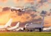 Passenger jets on airport tarmac with one aircraft landing at sunset