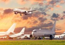 System Cracks Exposed – Triggers Airport Gridlock Passenger jets on airport tarmac with one aircraft landing at sunset