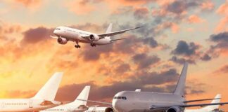 Passenger jets on airport tarmac with one aircraft landing at sunset
