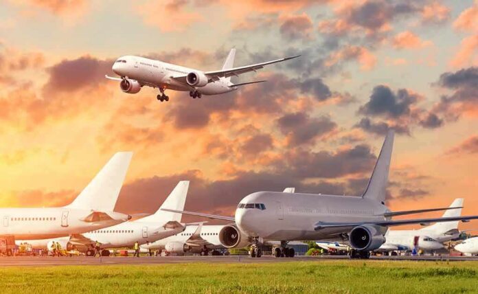 shutterstock_1711237150 Passenger jets on airport tarmac with one aircraft landing at sunset