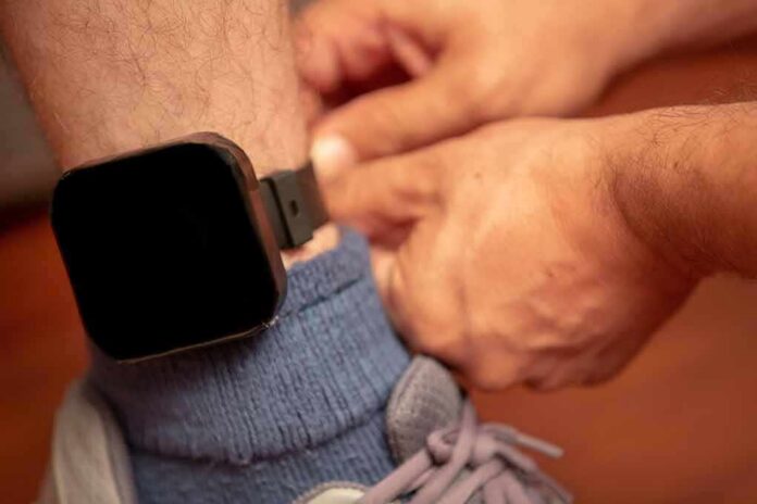Person fastening an ankle monitor on a leg