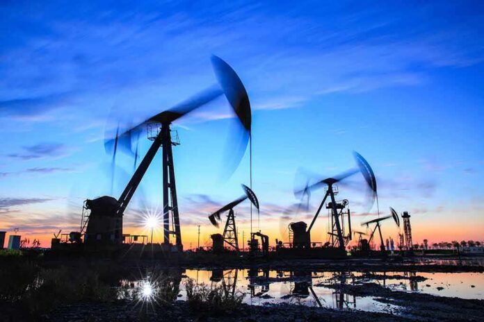 Oil pumpjacks operating at sunset over a reflective wet field