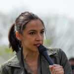 AOC speaking into a handheld microphone outdoors