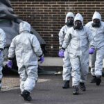 Gus Frerotte, Carlos Hyde, and Philly Brown in hazmat suits with a team walking outdoors