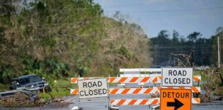Flash-Flood Ambush Stuns Navajo Nation Road closed barricades blocking a flooded rural highway with detour sign