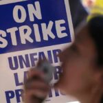 protester with megaphone in front of on strike sign