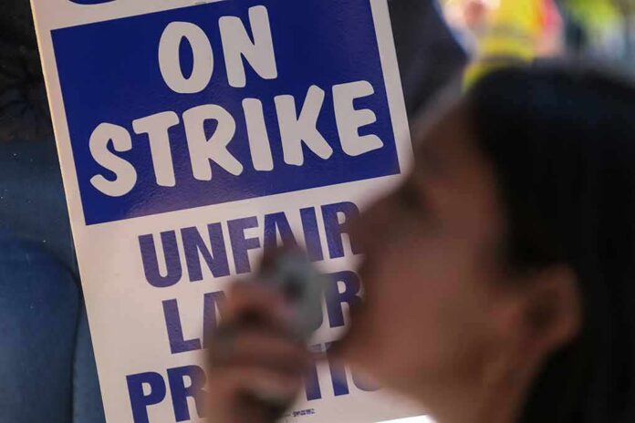 protester with megaphone in front of on strike sign