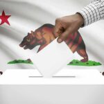 Hand casting a ballot into a box in front of the California flag