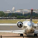 Private jet on airport taxiway with U.S. Capitol in background