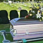 casket with floral arrangement at outdoor graveside service