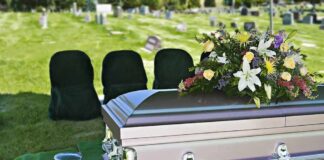 casket with floral arrangement at outdoor graveside service
