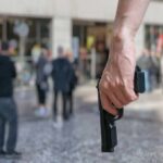 Person holding a handgun in a crowded public area