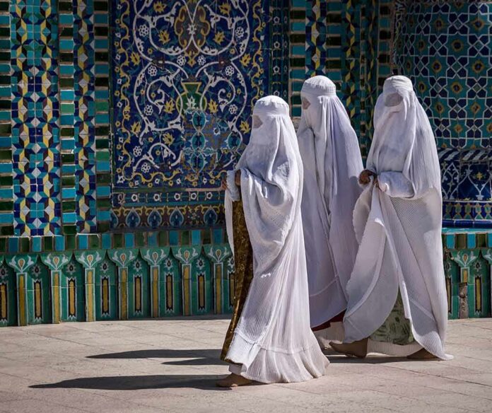 shutterstock_525952132 Three women in white veils walking past ornate blue tilework