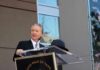 Bill Maher speaks at a podium during an outdoor event
