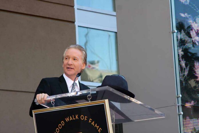 Bill Maher speaks at a podium during an outdoor event