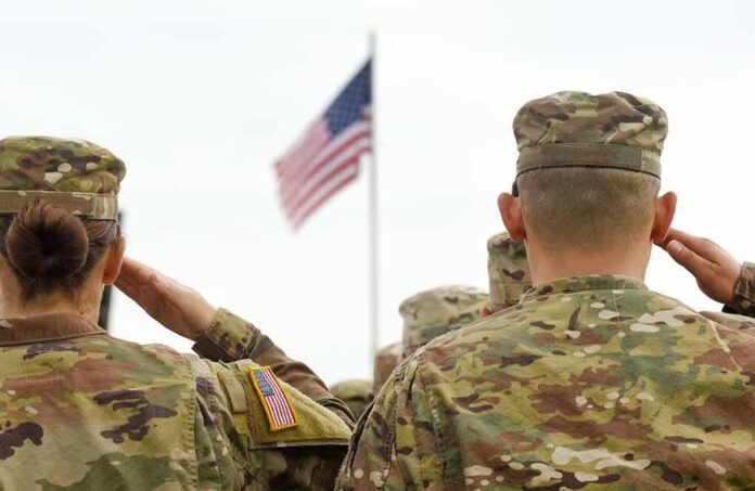 Soldiers in camouflage uniforms salute a U.S. flag