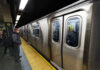 Subway train at platform with passengers inside and man waiting