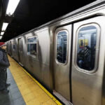 Subway train at platform with passengers inside and man waiting