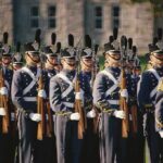 Group of uniformed cadets marching with rifles; named individuals: Zach Zenner, Griff Whalen, Patrick DiMarco, Freddie Williams II, Daryl Smith, Timmy Jernigan, Walter Jones
