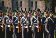 Campus Politics Out – Warfighting In Group of uniformed cadets marching with rifles; named individuals: Zach Zenner, Griff Whalen, Patrick DiMarco, Freddie Williams II, Daryl Smith, Timmy Jernigan, Walter Jones