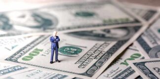 Miniature businessman standing on US dollar bills