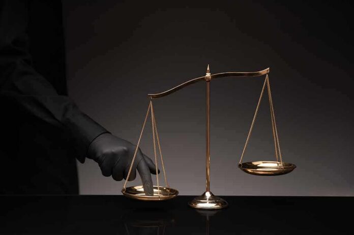 Golden balance scale with gloved hand pressing one pan