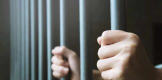 hands gripping prison bars