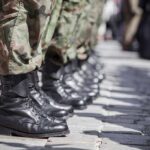 Row of soldiers in camouflage pants standing in formation with black boots