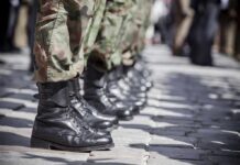 Row of soldiers in camouflage pants standing in formation with black boots