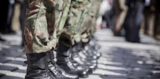 Row of soldiers in camouflage pants standing in formation with black boots