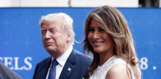two adults at an event, one smiling in a white dress