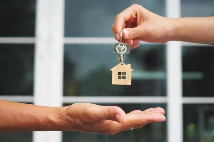 Hands exchanging house-shaped keychain and keys