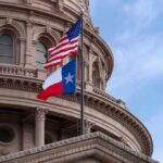 Texas and U.S. flags in front of a capitol building dome