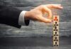 Hand selecting a top block with a red figure from a stack of employee icons