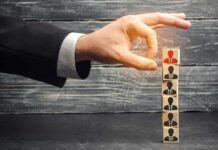 Hand selecting a top block with a red figure from a stack of employee icons