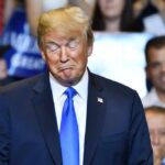Donald Trump with eyes closed and pursed lips at an event