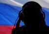 silhouetted person wearing headphones before a tricolor flag