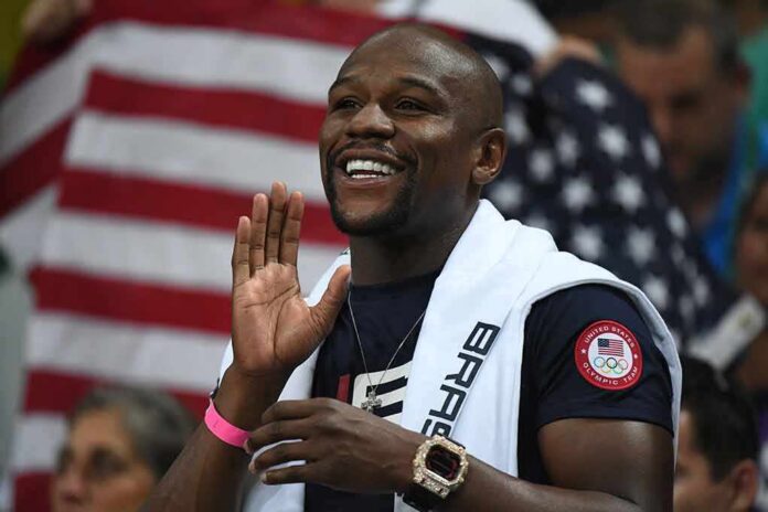 Floyd Mayweather Jr. smiling and cheering with a towel over his shoulders