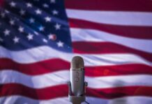 Final Showdown, High Stakes: Michigan On Edge Microphone in front of an American flag backdrop